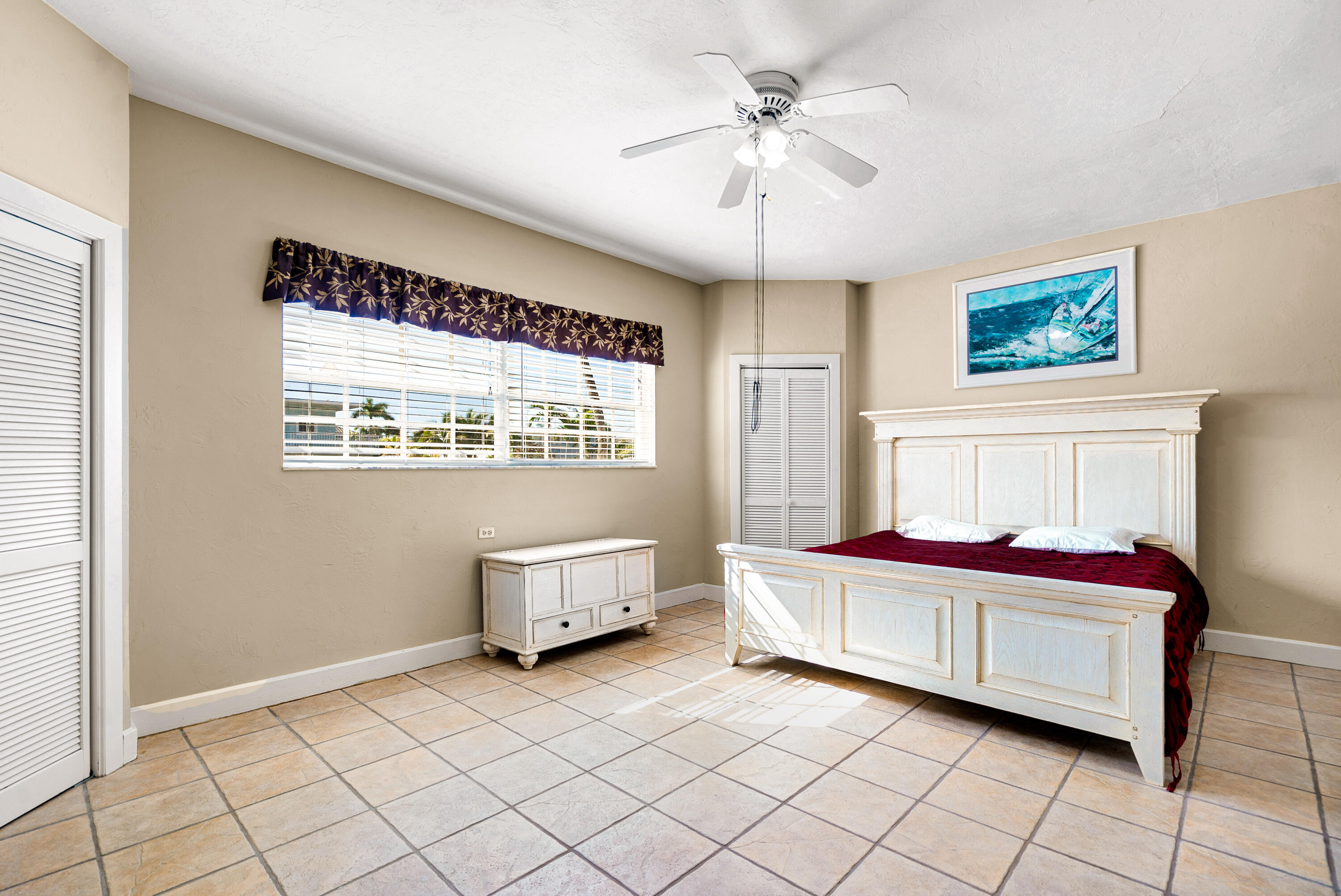 239 Atlantic Boulevard Key Largo, FL 33037 - Photo 20 of 50 a spacious bedroom with a bed and a chandelier