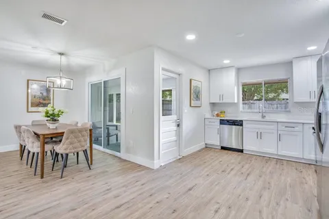 a kitchen with a table chairs a sink dishwasher refrigerator and cabinets