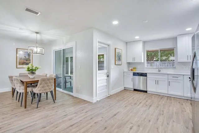 a kitchen with a table chairs a sink dishwasher refrigerator and cabinets