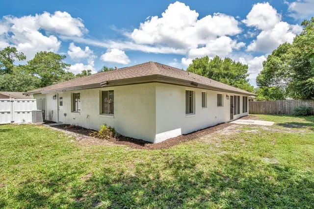 a view of a backyard with large trees and wooden fence