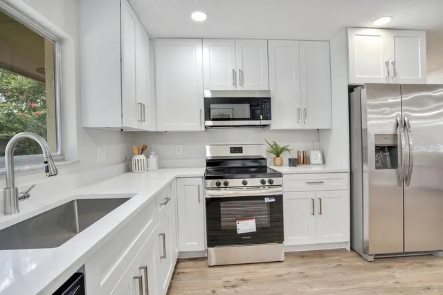 a kitchen with stainless steel appliances granite countertop a sink stove and refrigerator
