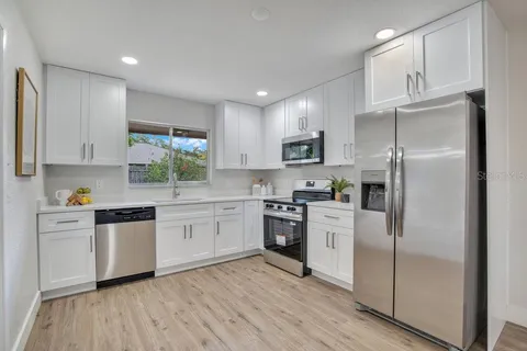 a kitchen with a refrigerator a sink a stove and cabinets