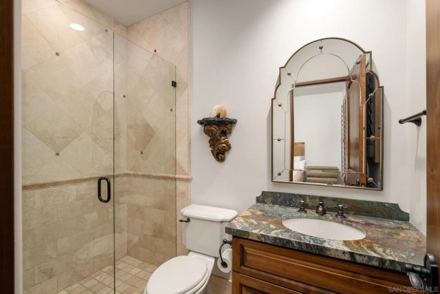 a bathroom with a granite countertop toilet sink and mirror