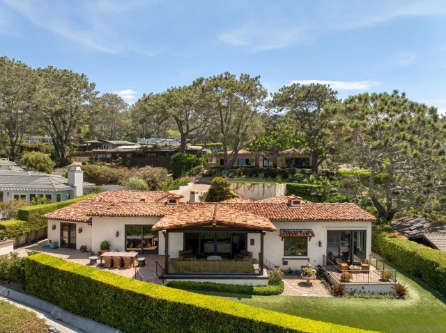 a front view of a house with swimming pool and trees in the background
