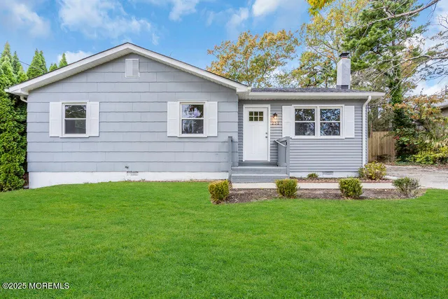 a front view of a house with garden and two chairs