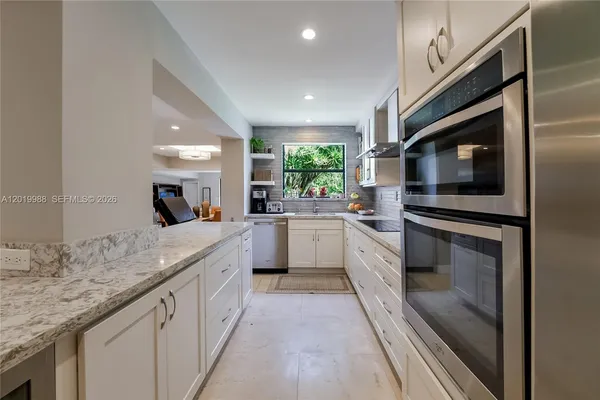 a large kitchen with stainless steel appliances kitchen island granite countertop a large counter top space a stove and cabinets