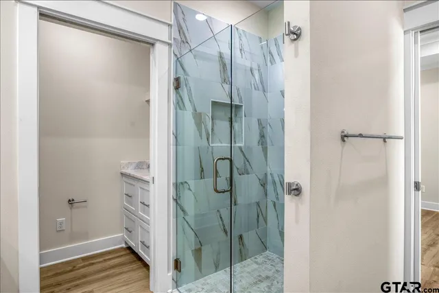 a bathroom with a granite countertop sink a mirror and shower view