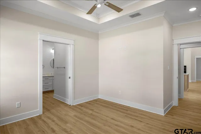 an empty room with wooden floor and fan