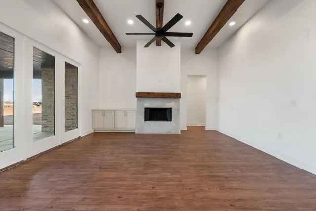 a view of an empty room with a fireplace and a ceiling fan
