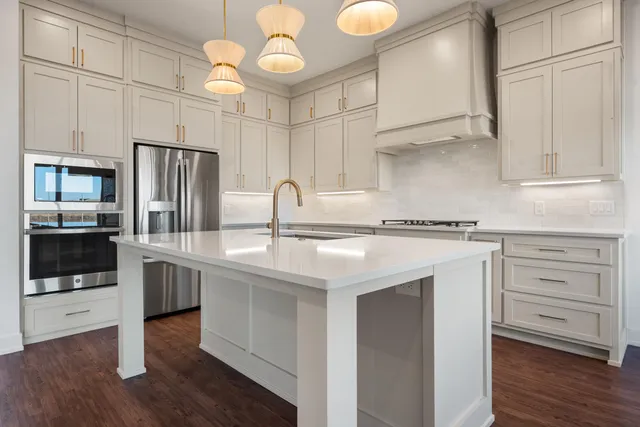 a kitchen with kitchen island granite countertop a sink cabinets and stainless steel appliances