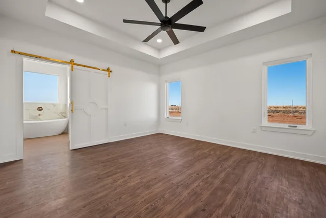 an empty room with wooden floor and a ceiling fan