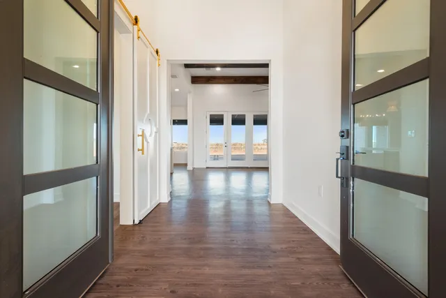 a view of a hallway with wooden floor and a glass door shower