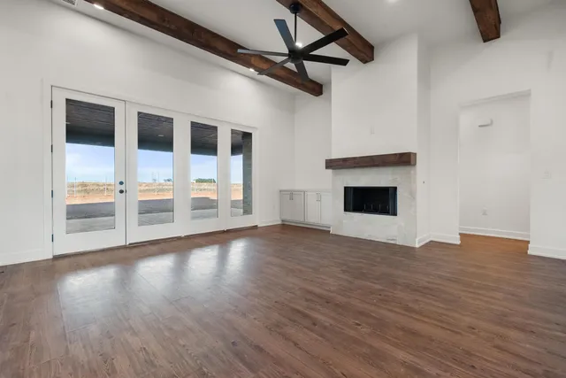 a view of an empty room with wooden floor fireplace and a window