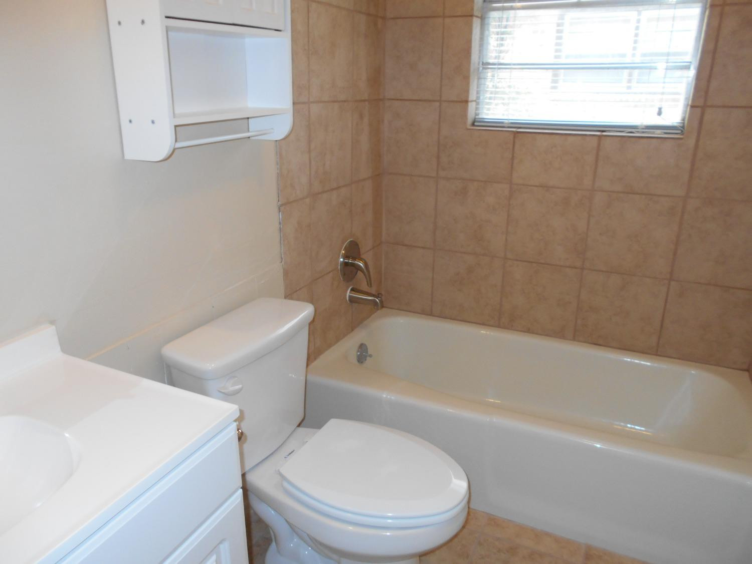 5401 14th Street Lubbock, TX 79416 - Photo 8 of 17 a white toilet and tub sitting next to a bathroom sink