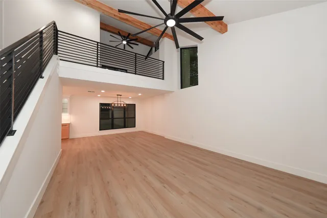 a view of a hallway with wooden floor and a ceiling fan