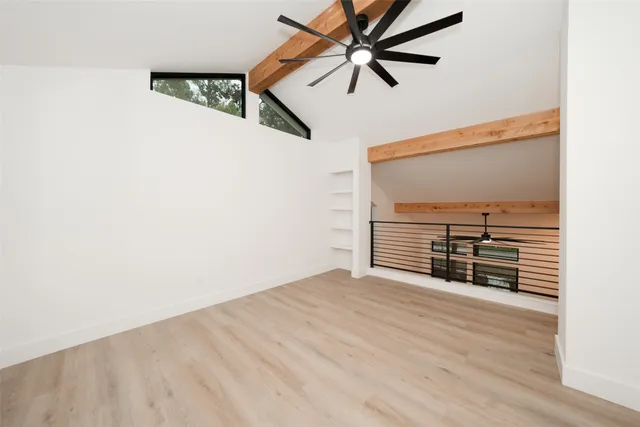 an empty room with ceiling fan and windows