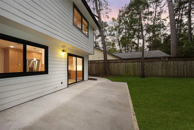 a view of a backyard with wooden fence and large trees
