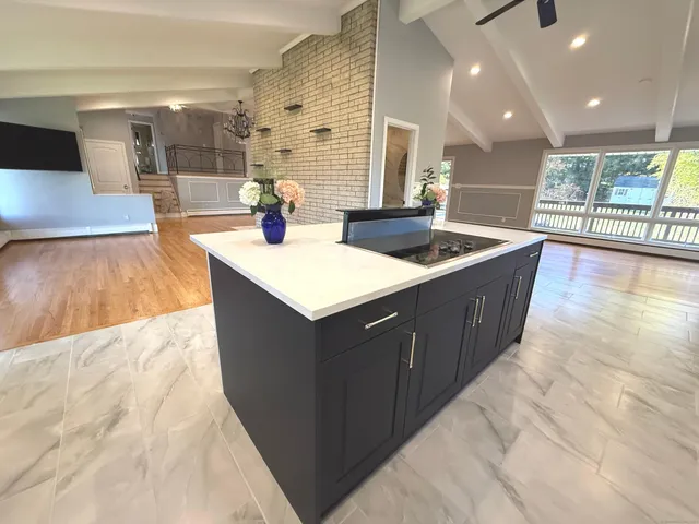 a large kitchen with stainless steel appliances a large counter top a stove a chimney a sink and a refrigerator