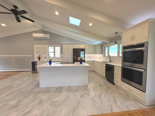 a living room with stainless steel appliances kitchen island granite countertop a stove a sink dishwasher a microwave oven and a dining table with wooden floor