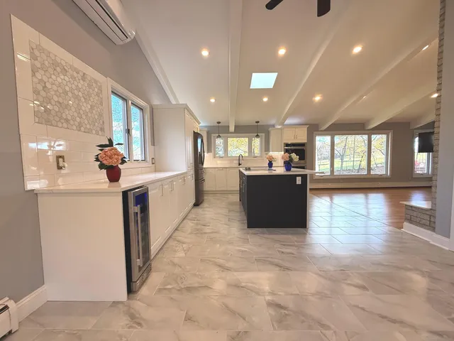 a living room with stainless steel appliances kitchen island granite countertop a refrigerator and a stove top oven