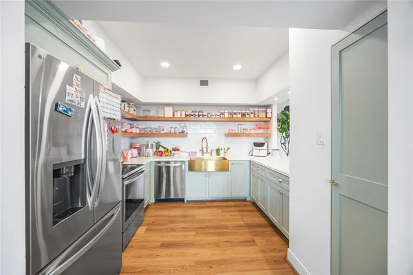 a kitchen with stainless steel appliances granite countertop a sink a stove and a refrigerator