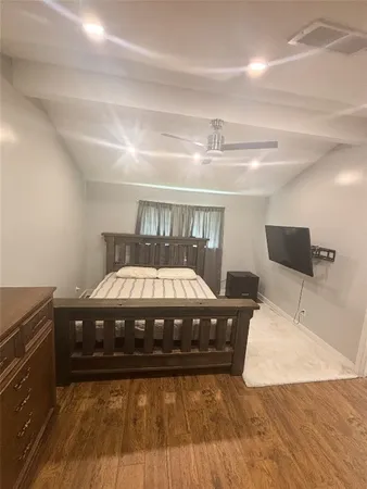 a spacious bedroom with a bed and wooden floor