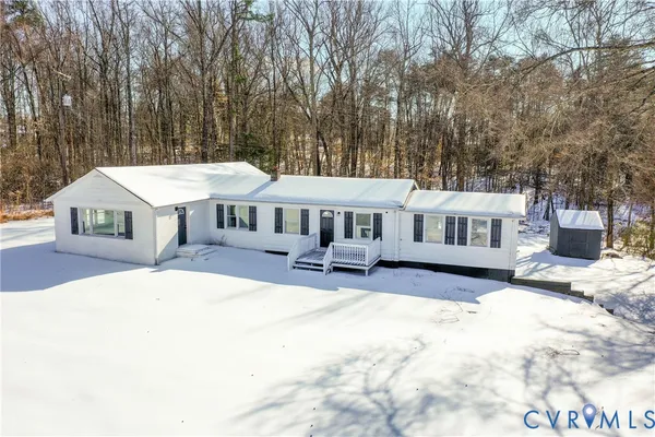 a front view of a house with a yard outdoor seating and covered with trees