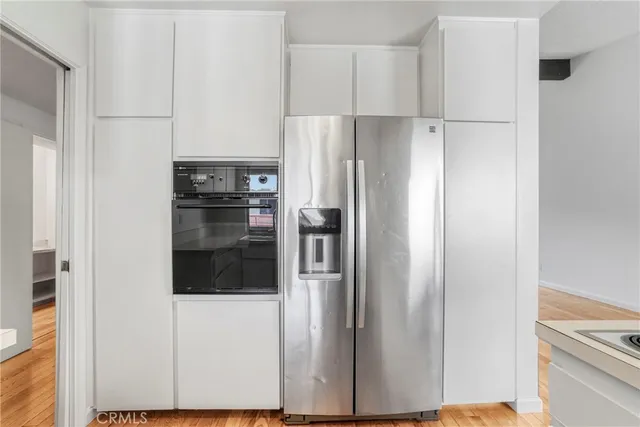 a kitchen with stainless steel appliances granite countertop a sink stove and white cabinets with wooden floor