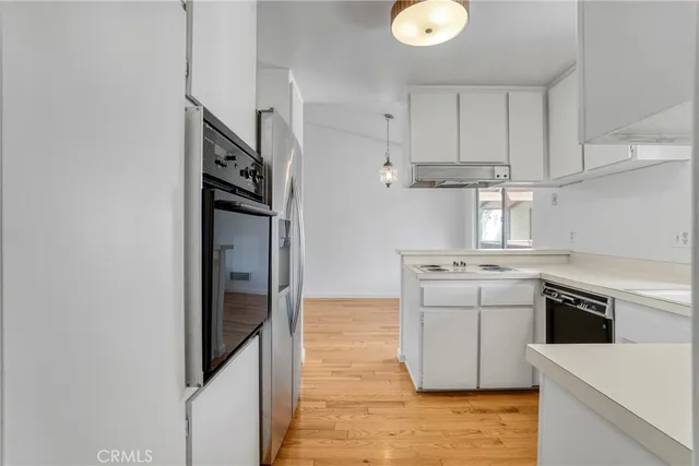 an empty room with wooden floor cabinet and windows
