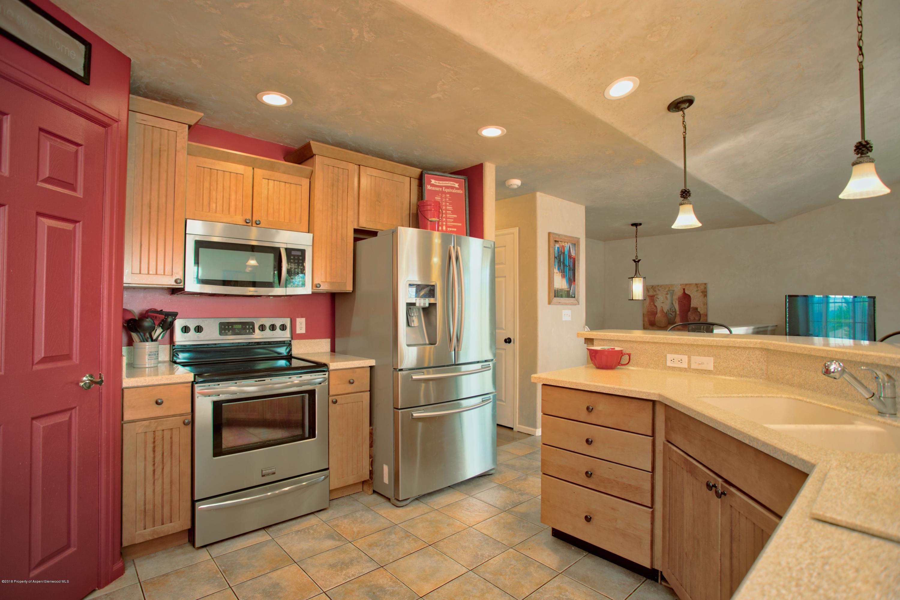 841 Hickory Drive Rifle, CO 81650 - Photo 6 of 20 a kitchen with stainless steel appliances kitchen island granite countertop a refrigerator oven stove a sink dishwasher and white cabinets with wooden floor