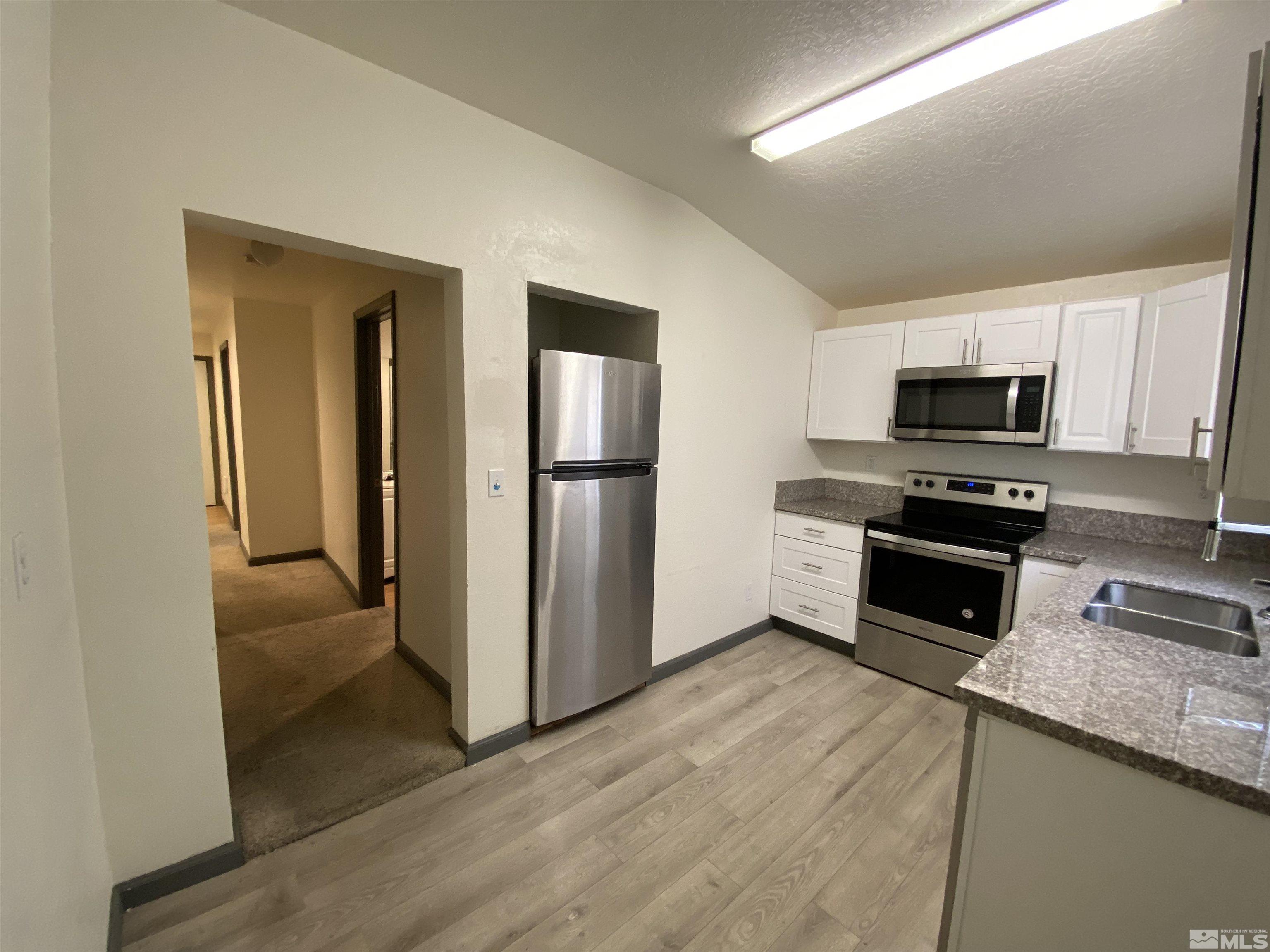 656 Spokane Street Reno, NV 89512 - Photo 4 of 31 a kitchen with granite countertop a refrigerator and a stove top oven