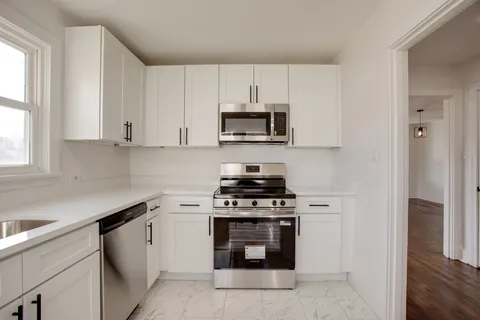a kitchen with cabinets stainless steel appliances and a window
