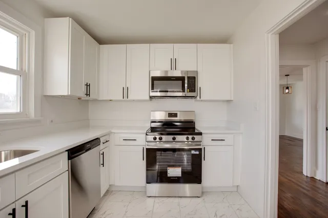 a kitchen with cabinets stainless steel appliances and a window