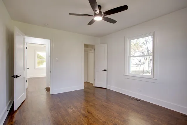 a view of an empty room with a window and wooden floor