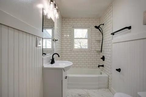 a bathroom with a sink a bathtub and a window