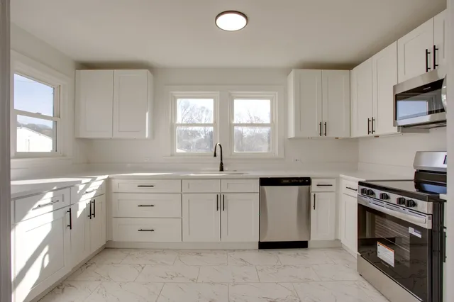 a kitchen with granite countertop white cabinets and stainless steel appliances