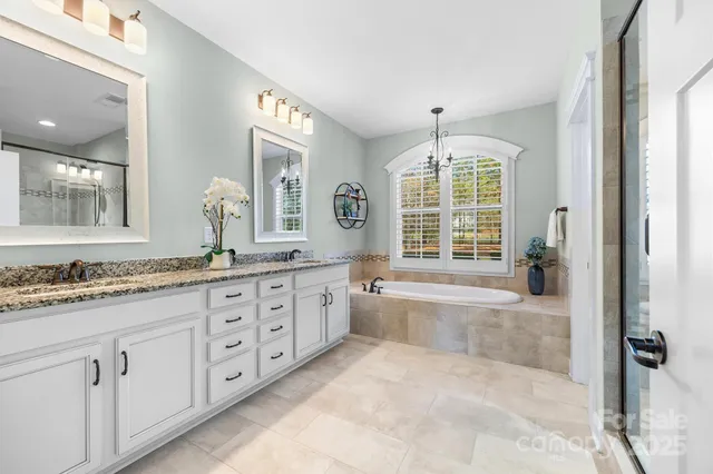 a spacious bathroom with sinks granite countertop tub a double vanity sink a window and a mirror