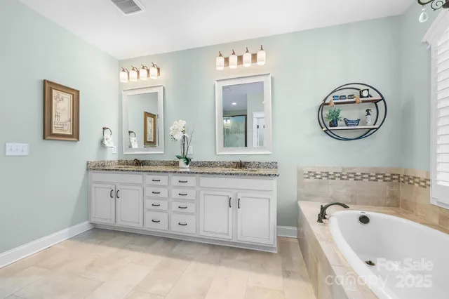 a bathroom with a granite countertop sink mirror and bathtub