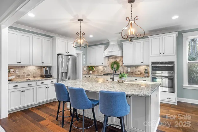 a kitchen with stainless steel appliances kitchen island granite countertop a sink a center island and cabinets