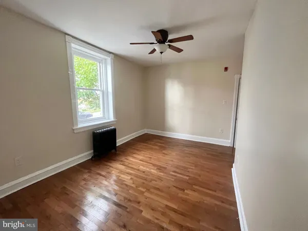 an empty room with wooden floor fan and windows