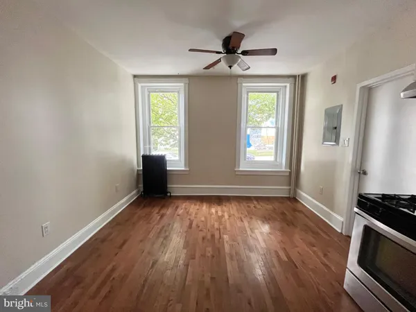 a view of an empty room with a window and wooden floor