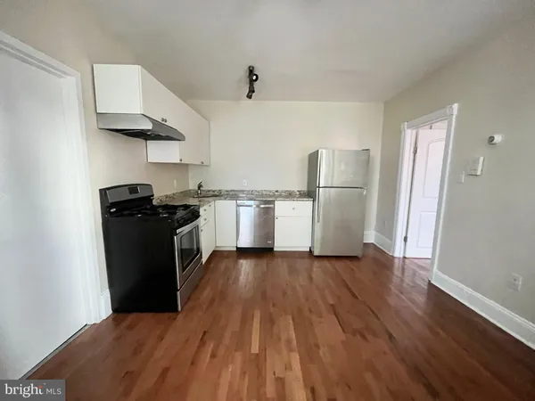 a kitchen with a sink a refrigerator and wooden floor