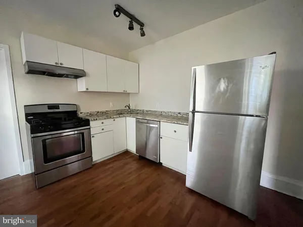 a kitchen with a refrigerator a stove top oven a sink and cabinets