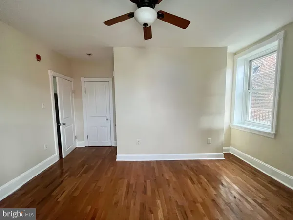 a view of empty room with wooden floor and fan
