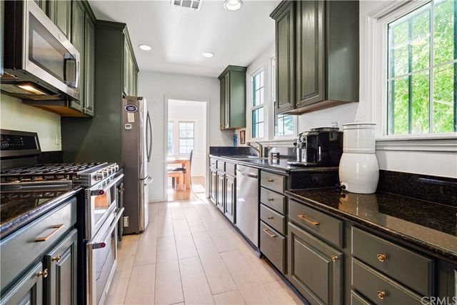a kitchen with stainless steel appliances granite countertop a stove a sink and a refrigerator