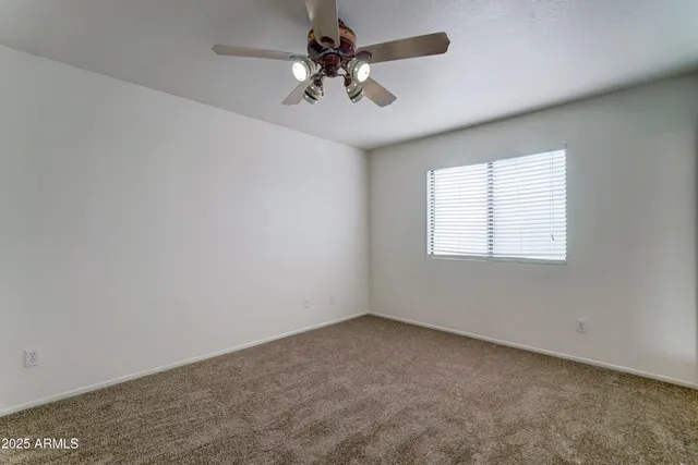 an empty room with a chandelier fan and windows