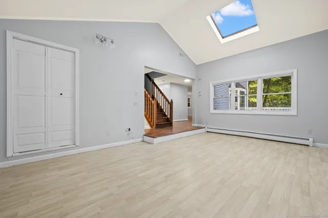 a view of an empty room with a window and wooden floor