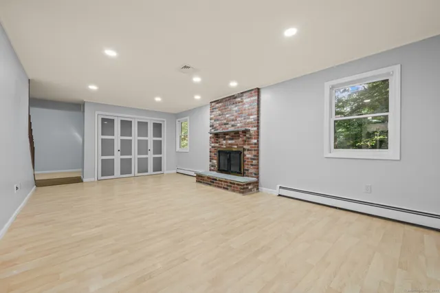 a view of an empty room with a window and fireplace