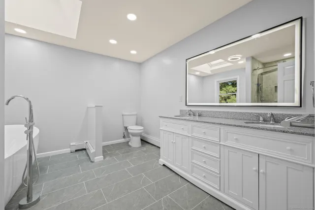 a spacious bathroom with a double vanity sink a mirror and a toilet