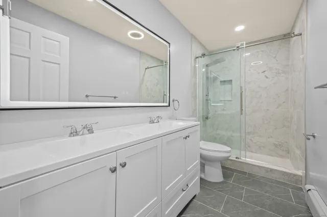 a bathroom with a shower sink vanity mirror and toilet